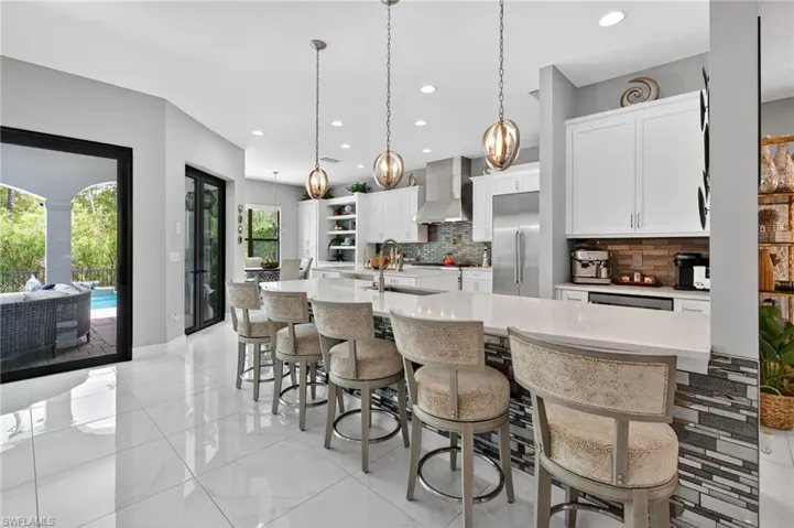 Kitchen with backsplash, a kitchen breakfast bar, white cabinetry, decorative light fixtures, and open shelves
