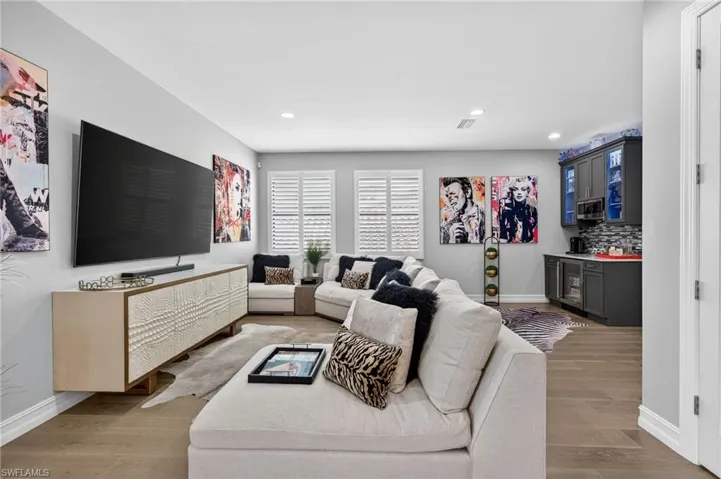 Living room with a dry bar, light wood-style flooring, recessed lighting, and beverage cooler
