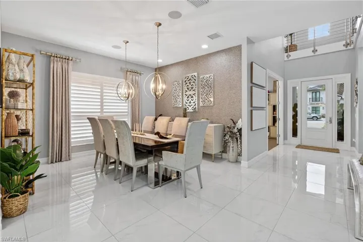 Dining room with a chandelier, wallpapered walls, an accent wall, recessed lighting, and light marble finish floors