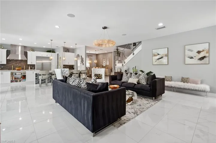 Living room featuring recessed lighting, light marble finish floors, and stairway