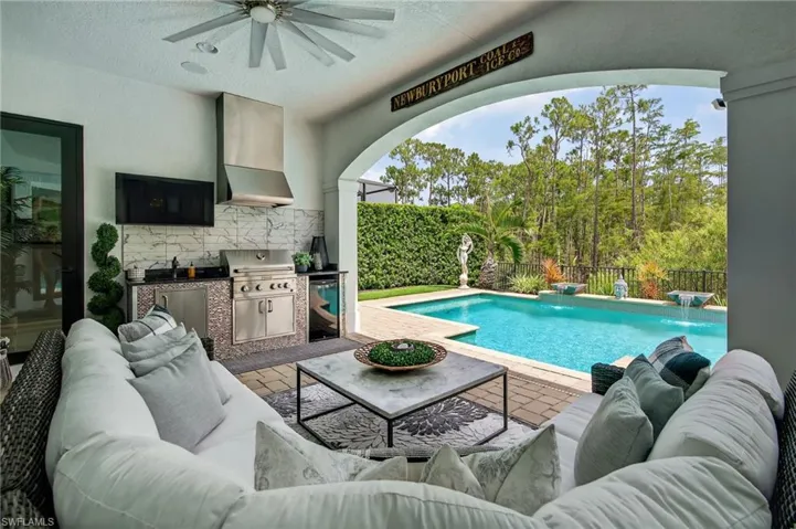 View of pool with outdoor lounge area, exterior kitchen, a fenced backyard, a patio area, and a ceiling fan
