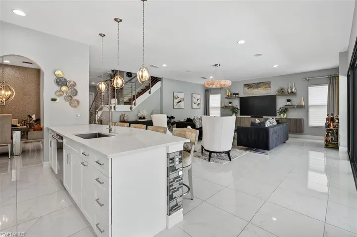 Kitchen with open floor plan, a chandelier, pendant lighting, light stone counters, and white cabinetry
