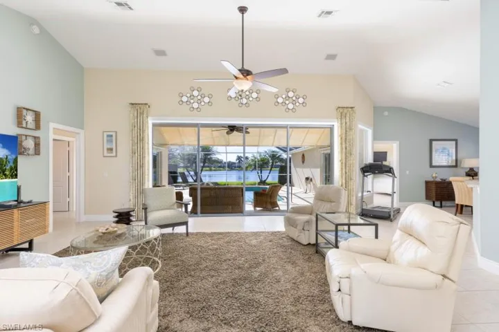 Living room featuring ceiling fan, vaulted ceiling, a wealth of natural light, and light tile patterned flooring