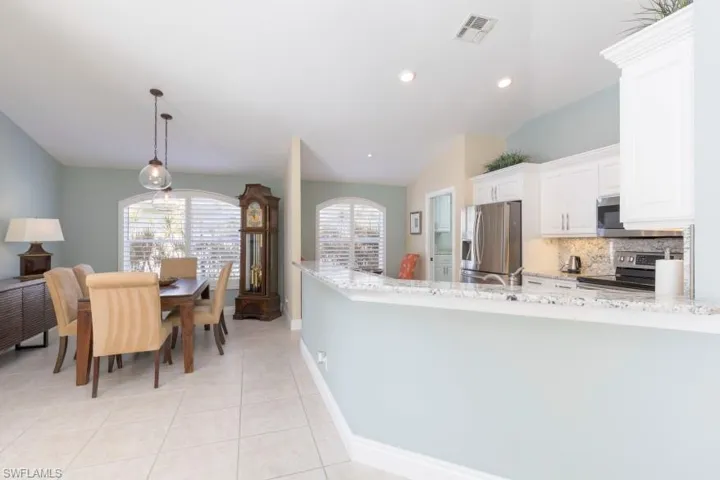 Kitchen featuring lofted ceiling, hanging light fixtures, light tile patterned floors, appliances with stainless steel finishes, and white cabinetry