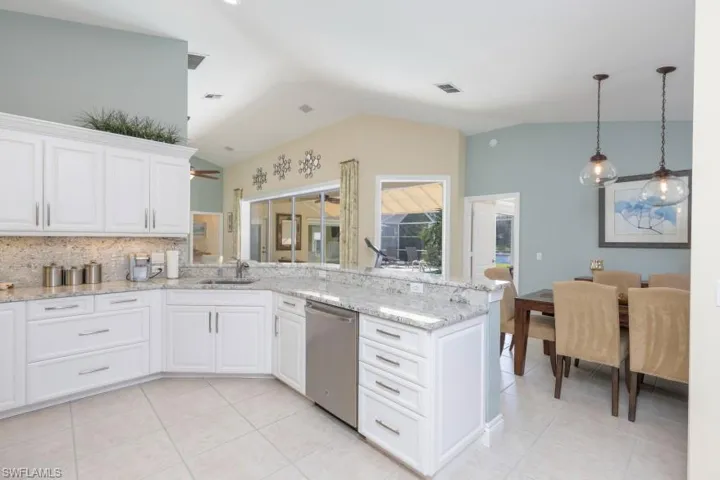 Kitchen featuring white cabinets, vaulted ceiling, ceiling fan, sink, and dishwasher