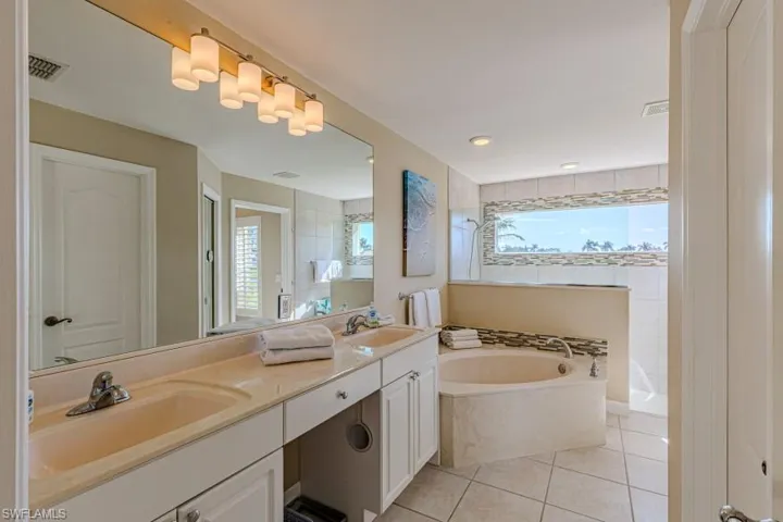 Bathroom with vanity, plenty of natural light, tile patterned flooring, and a washtub
