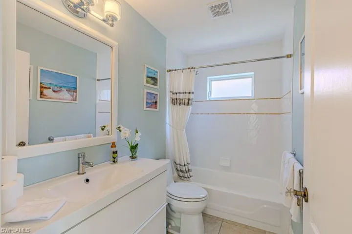 Full bathroom with tile patterned floors, vanity, toilet, and shower / tub combo with curtain