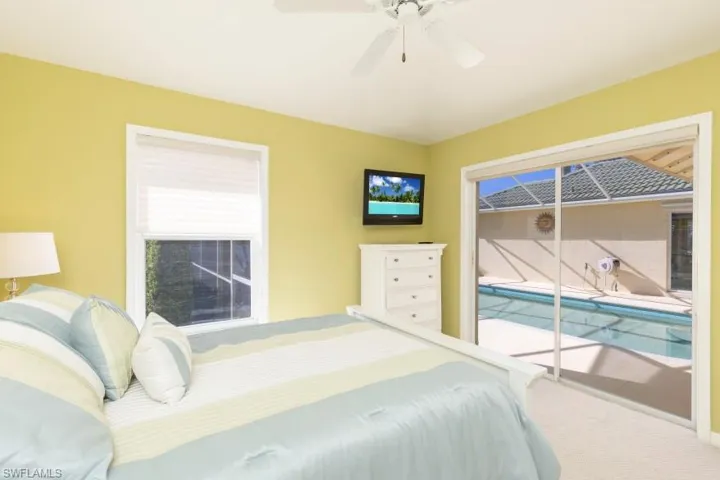 Carpeted bedroom featuring access to outside and ceiling fan