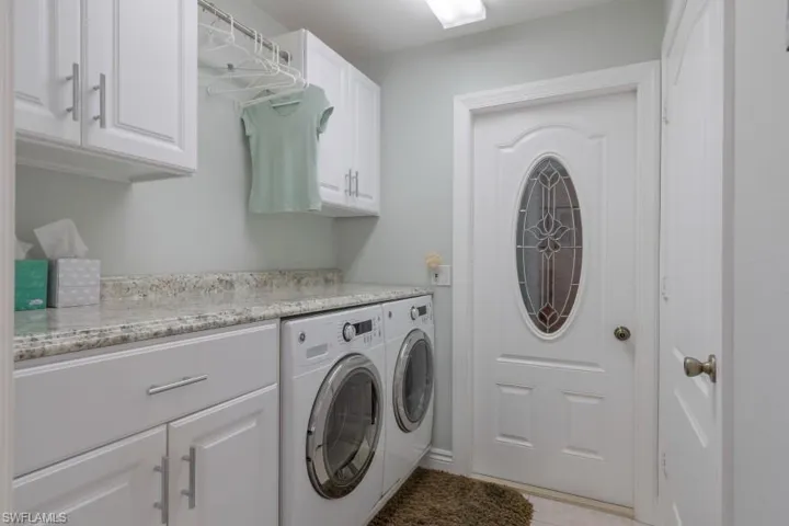 Laundry area featuring cabinets, separate washer and dryer, and light tile patterned floors