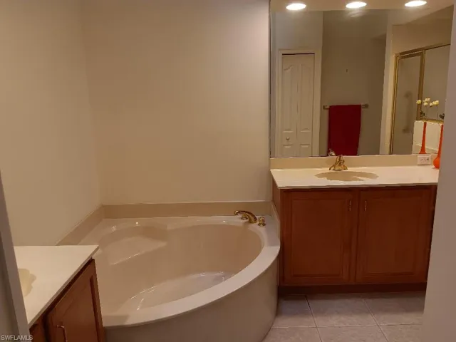 Bathroom featuring tile patterned flooring, vanity, and a tub to relax in