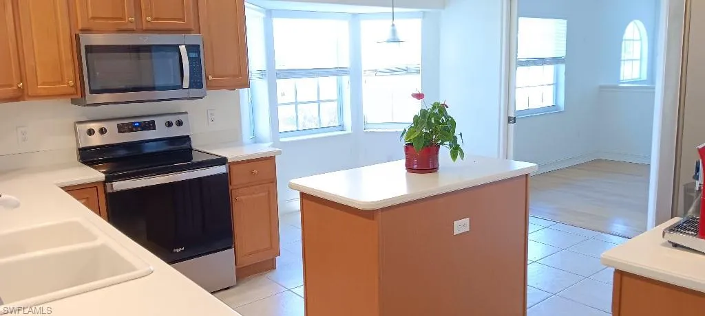 Kitchen with appliances with stainless steel finishes, pendant lighting, light tile patterned floors, and a wealth of natural light
