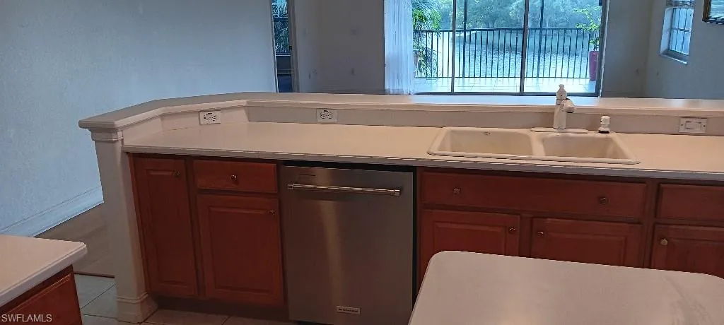 Kitchen with sink, stainless steel dishwasher, and light tile patterned floors