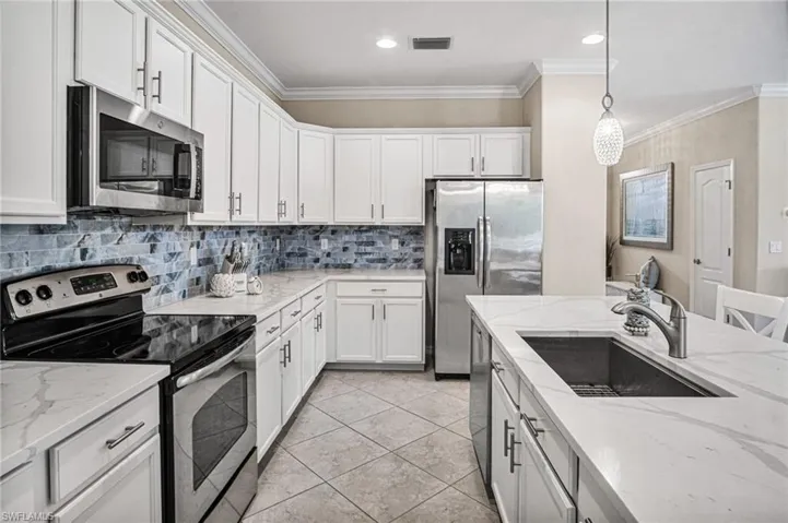 BRAND-NEW WHITE QUARTZ COUNTERTOPS AND MARBLED SUBWAY TILE BACKSPLASH (2026), white cabinetry, newer microwave and dishwasher, and a breakfast bar ideal for casual dining and entertaining.