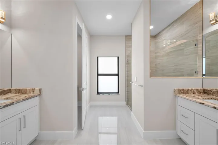 Bathroom with two vanities, a stall shower, and recessed lighting