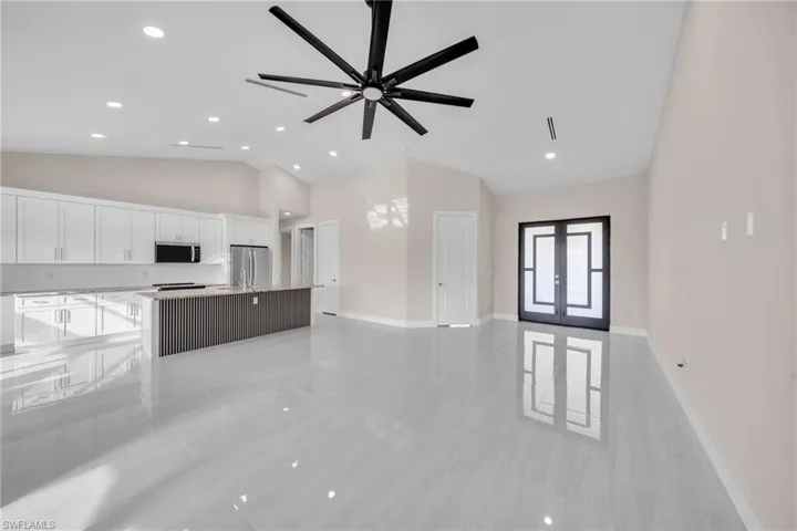 Unfurnished living room with french doors, recessed lighting, a ceiling fan, and high vaulted ceiling