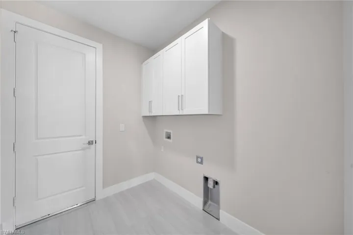 Washroom featuring hookup for an electric dryer, hookup for a washing machine, and cabinet space