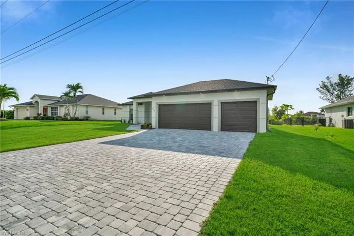 View of front of home featuring decorative driveway, stucco siding, and a garage