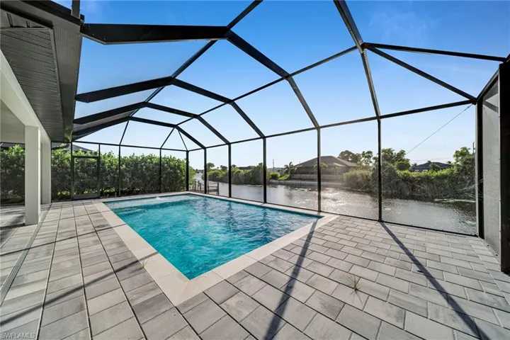 Outdoor pool with a sunroom, a lanai, a patio area, and a water view