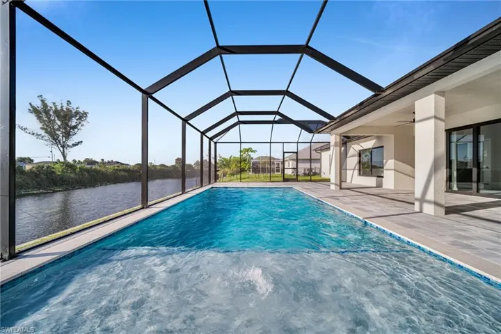 Swimming pool with a sunroom, a ceiling fan, a water view, a lanai, and a patio area