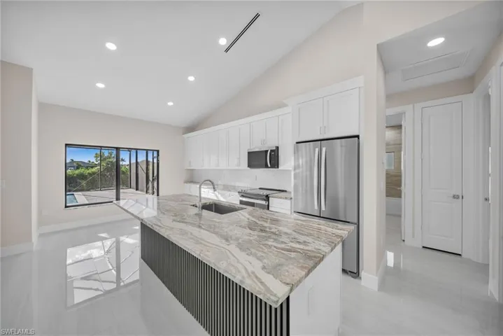 Kitchen featuring stainless steel appliances, recessed lighting, white cabinetry, light stone countertops, and decorative backsplash