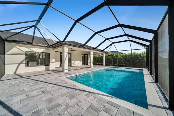 Outdoor pool with glass enclosure, a sunroom, ceiling fan, and a patio