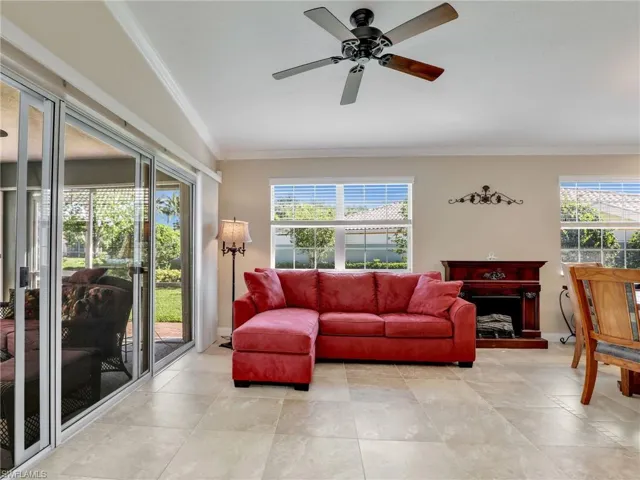 Tiled living room with crown molding, ceiling fan, and vaulted ceiling