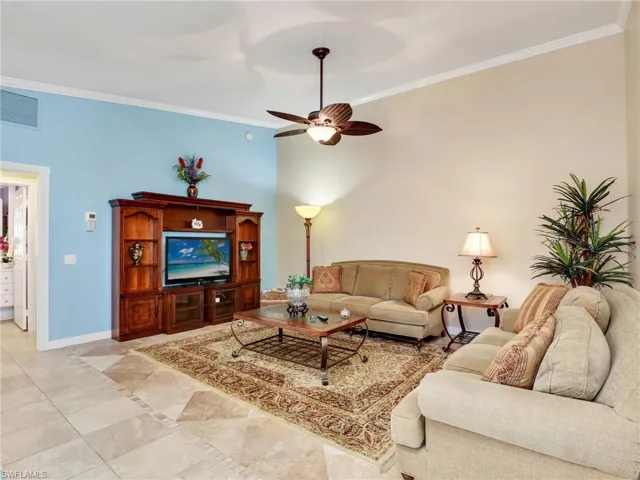 Living room featuring ceiling fan, ornamental molding, and light tile floors