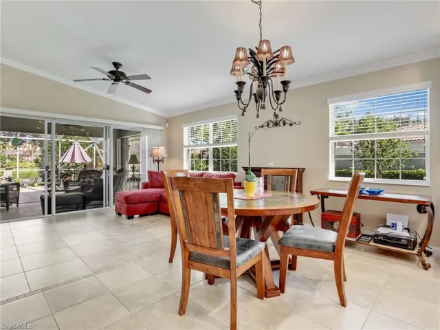 Tiled dining area featuring vaulted ceiling, ceiling fan with notable chandelier, and crown molding