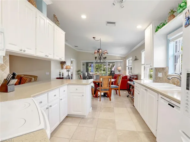 Kitchen featuring white dishwasher, crown molding, white cabinetry, kitchen peninsula, and tasteful backsplash