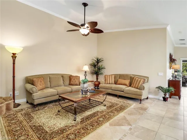 Living room featuring a towering ceiling, tile flooring, ornamental molding, and ceiling fan
