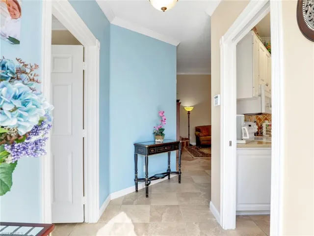 Hall with ornamental molding and light tile floors