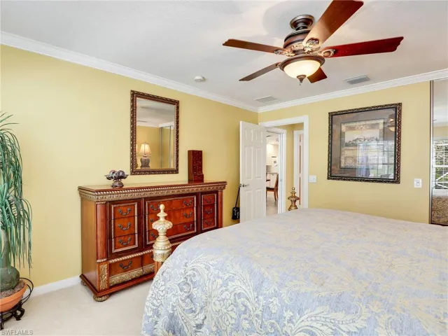 Carpeted bedroom featuring ornamental molding and ceiling fan