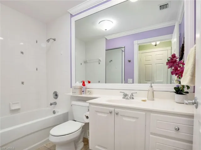 Full bathroom featuring ornamental molding, bathing tub / shower combination, tile floors, vanity, and toilet