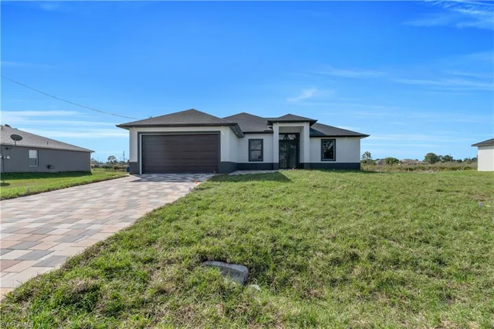 Prairie-style house featuring driveway, stucco siding, a front yard, and an attached garage