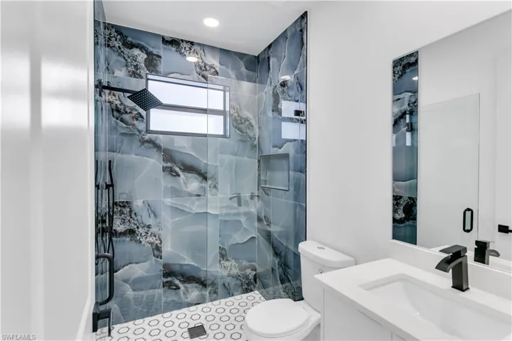 Bathroom with vanity and a marble finish shower