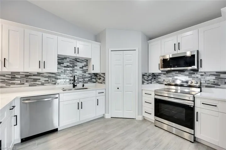 Kitchen featuring stainless steel appliances, a sink, light countertops, and white cabinets