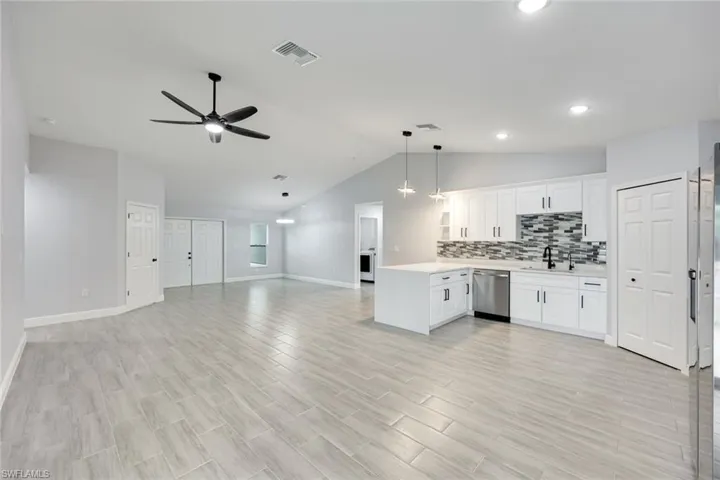 Kitchen with light countertops, visible vents, open floor plan, dishwasher, and a peninsula