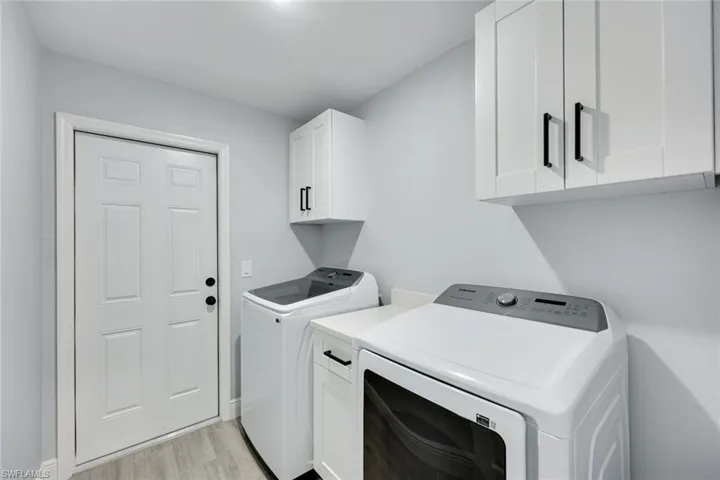 Laundry area featuring cabinet space, independent washer and dryer, and light wood finished floors