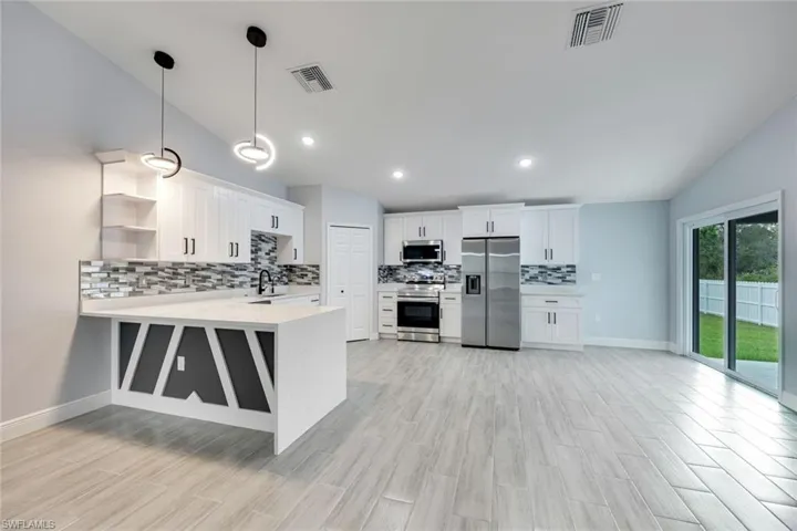 Kitchen featuring stainless steel appliances, light countertops, open shelves, and visible vents