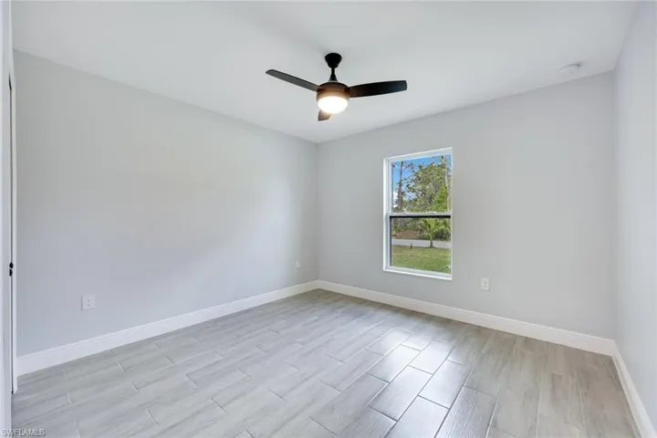 Empty room with ceiling fan, light wood finished floors, and baseboards