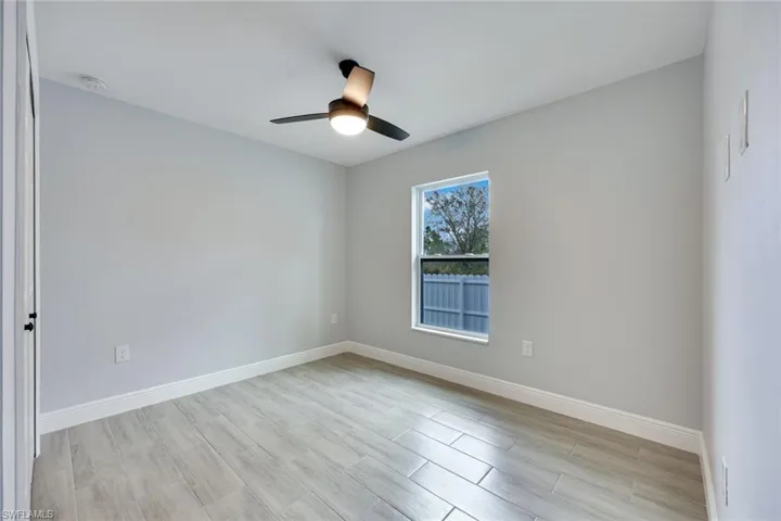 Empty room with a ceiling fan, light wood finished floors, and baseboards