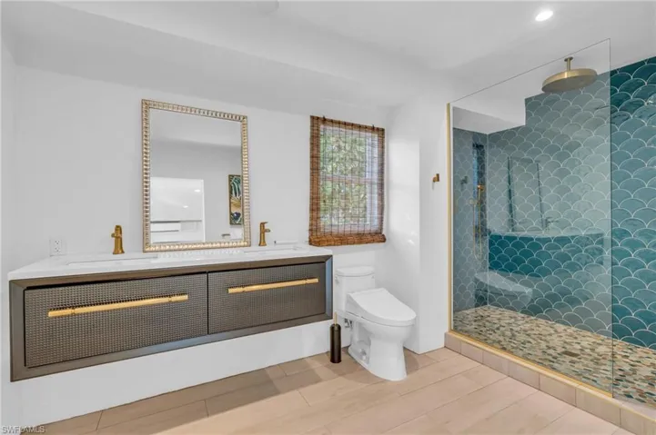 Full bathroom featuring a stall shower, double vanity, light wood-type flooring, and recessed lighting
