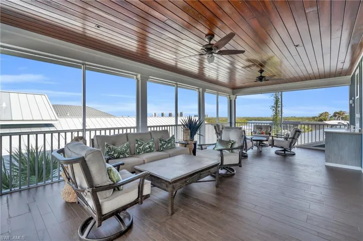 Sunroom / solarium featuring wood ceiling, wood finished floors, and a wall of windows
