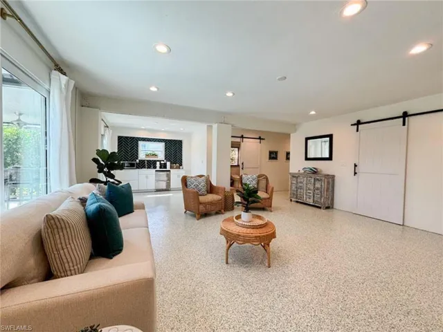 Living room featuring a barn door, recessed lighting, and speckled floor