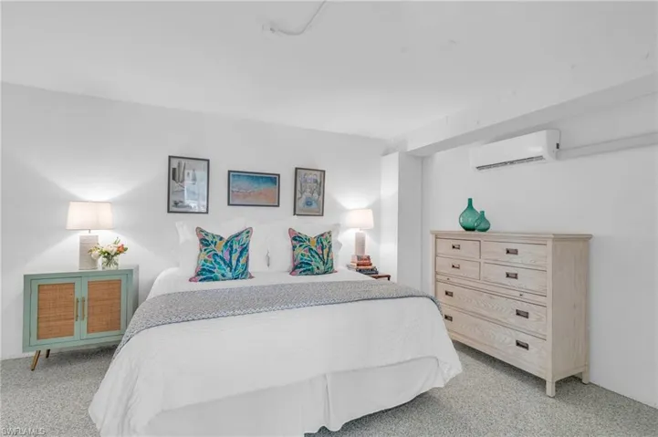 Bedroom with light colored carpet and an AC wall unit