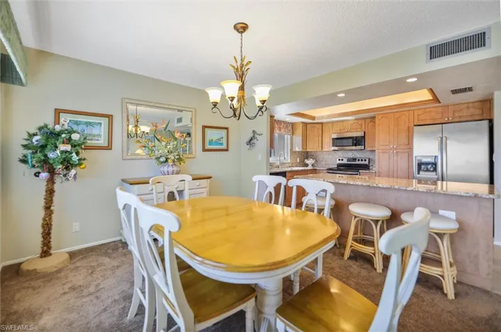 Carpeted dining area featuring a tray ceiling, a chandelier, and recessed lighting