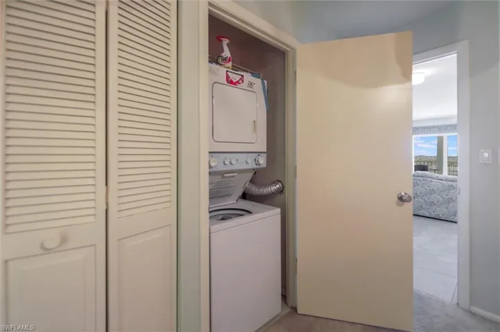 Washroom featuring estacked washer and dryer and light colored carpet