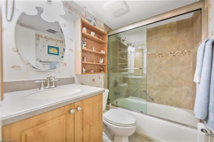 Bathroom with vanity and bath / shower combo with glass door