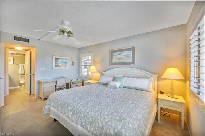 Bedroom with a textured ceiling, light colored carpet, and a ceiling fan