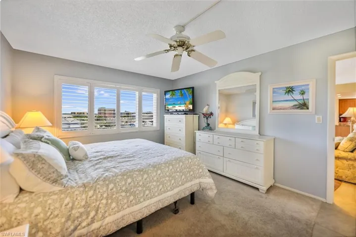 Bedroom with a textured ceiling, light colored carpet, and ceiling fan